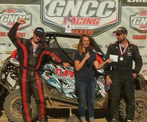 (From left) Navigator Chris Bithell, Racer Productions Media Manager Jen Kenyon and pilot Kyle Chaney discussed Chaney's second straight XC1 Modified class win while celebrating on the Wiseco John Penton GNCC podium in Ohio.
